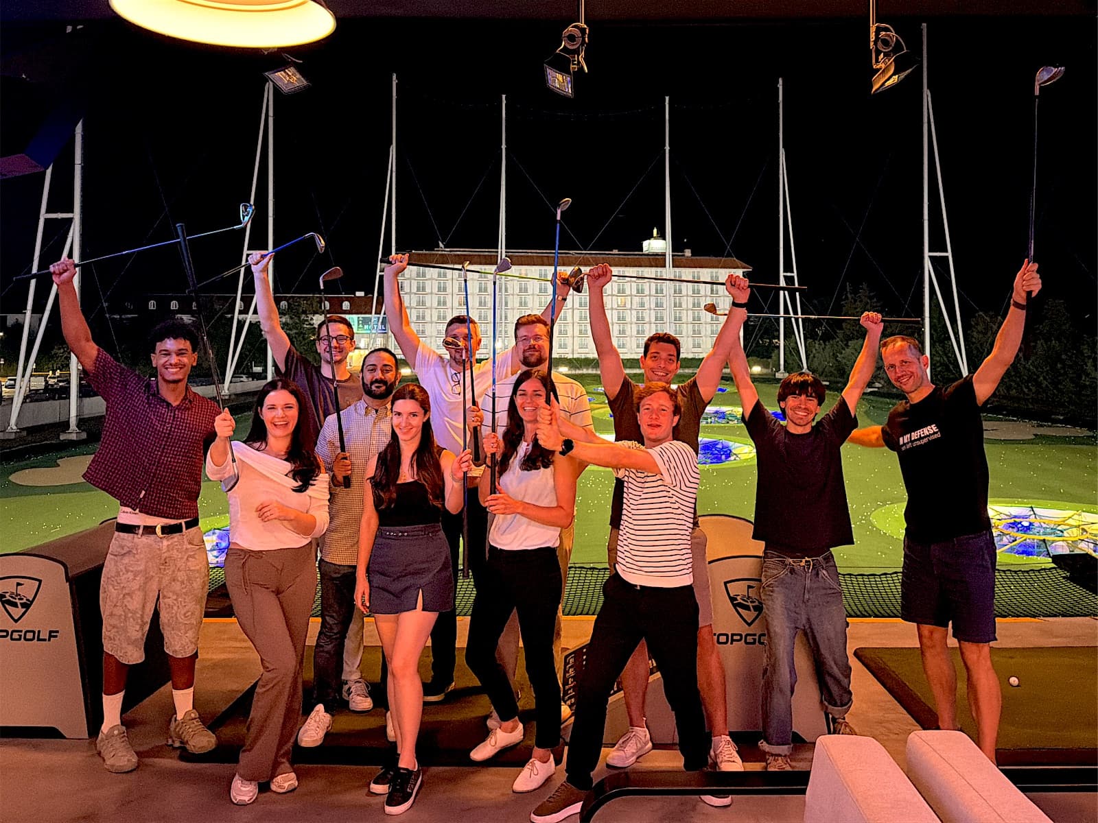 Das Senseven-Team mit erhobenen Golfschlägern beim Team-Event im Topgolf